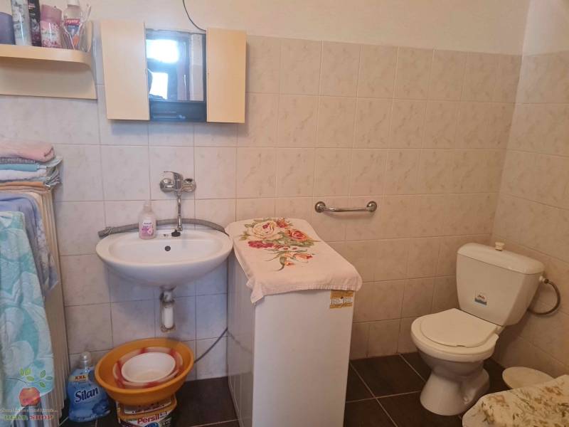 Kúpeľňa v rodinnom dome so zrkadlom, umývadlom, toaletou a práčkou.