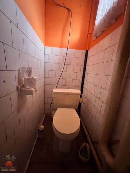 Toaleta v rodinnom dome s bielymi kachličkami a oranžovými stenami.